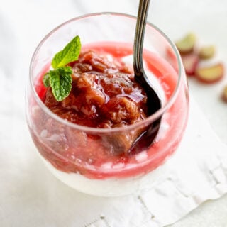 a glass with yogurt topped with compote with a spoon in it