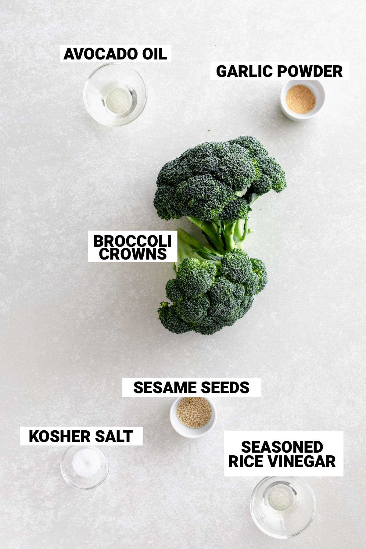 grilled broccoli ingredients including avocado oil, garlic powder, broccoli crowns, sesame seeds, kosher salt, and seasoned rice vinegar