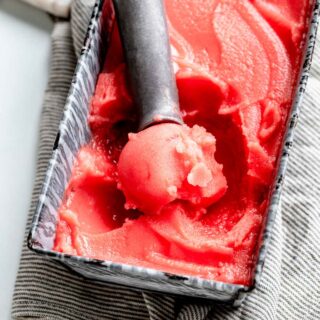 watermelon sorbet being scooped out of a bread pan