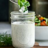 a fork dipping lettuce into a jar of ranch