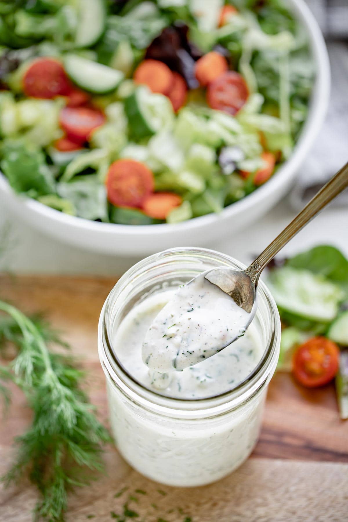 a spoon with ranch on it dipping into a jar of ranch