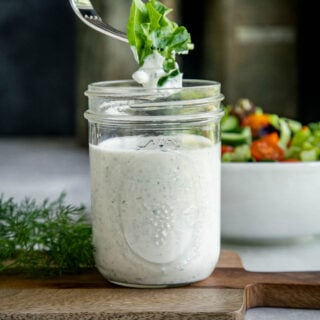 a fork dipping lettuce into a jar of ranch