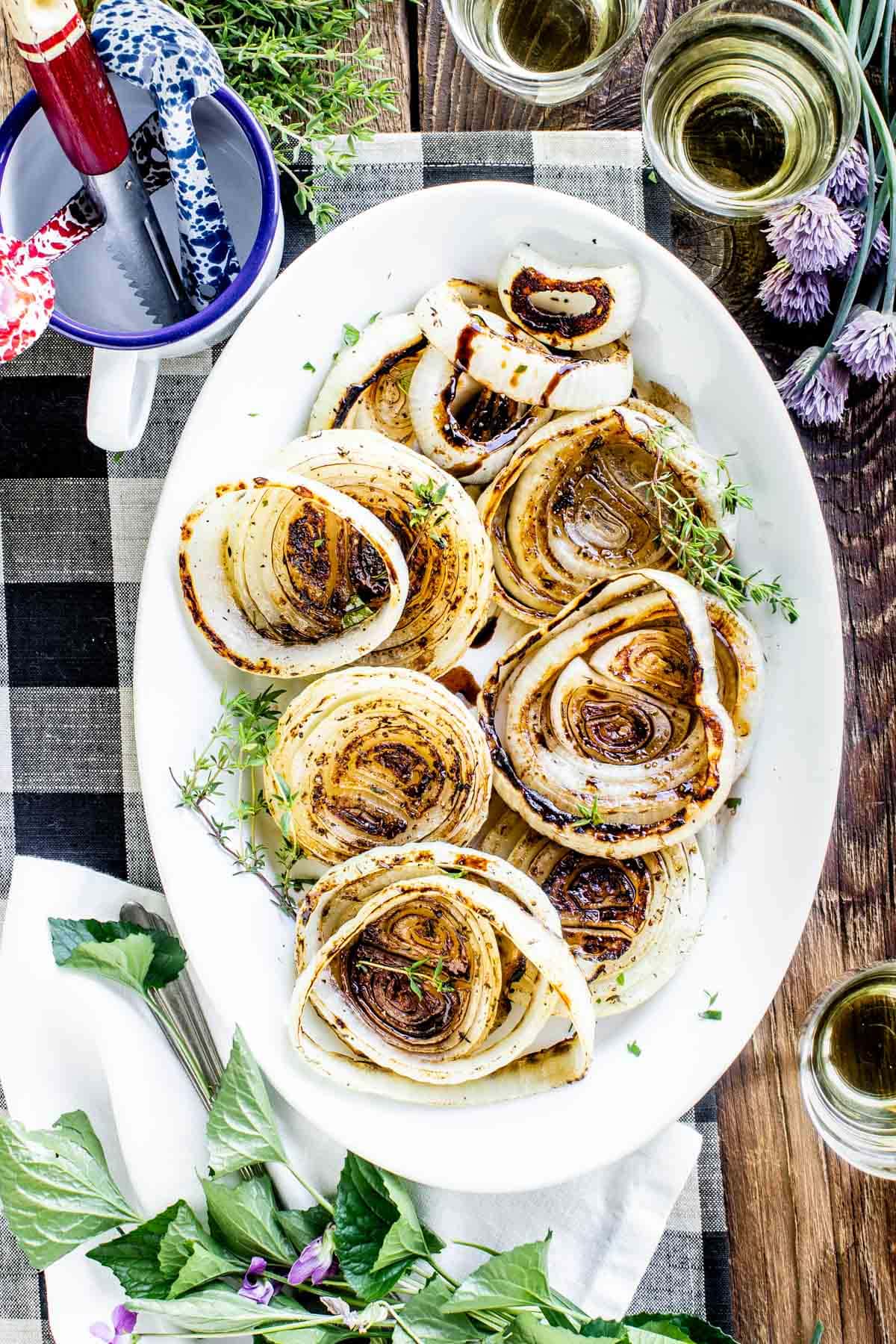 grilled onions sprinkled with thyme and drizzled with balsamic vinegar on a serving dish