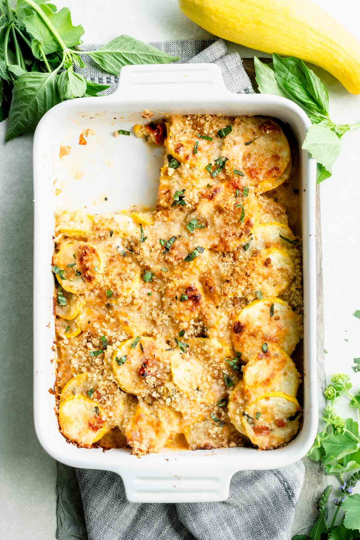 summer squash casserole with a scoop missing and sprinkled with browned breadcrumbs and herbs