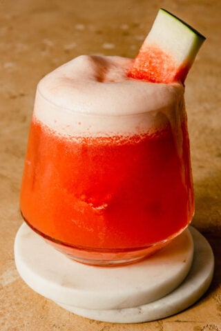 watermelon cocktail in a rocks glass set on two white coasters