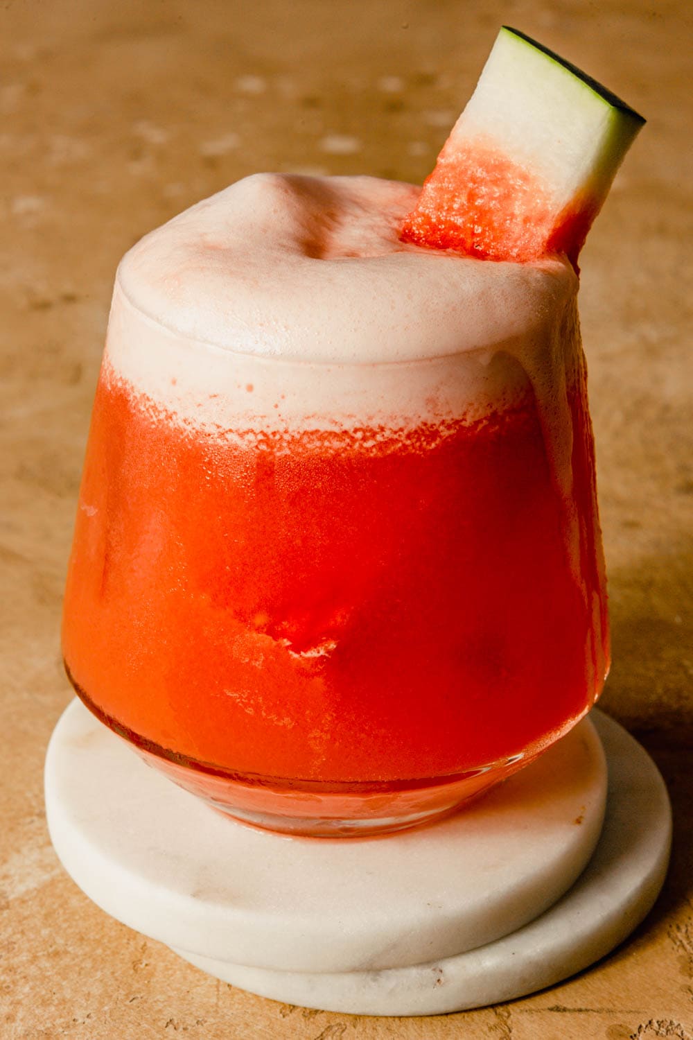 watermelon cocktail in a rocks glass set on two white coasters