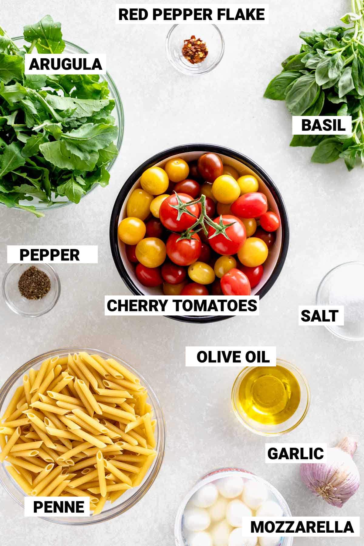 cherry tomatoes, penne pasta, arugula, basil, mozarella, and more ingredients for this caprese pasta salad