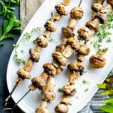 skewered grilled mushroom kebabs on a white platter