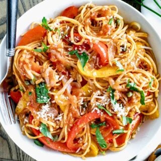 close up of a bowl of pasta with red and yellow pepper sauce