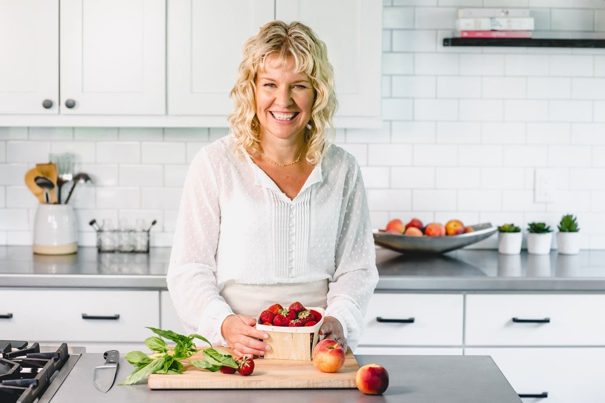 katie webster in a white kitchen with strawberries, basil and peaches