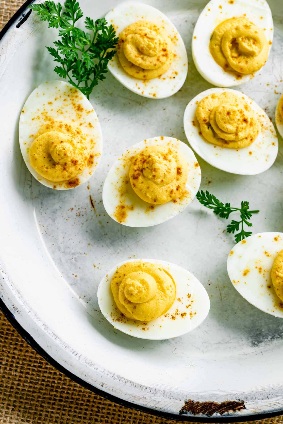 deviled eggs with paprika on them in an antique white pie tin