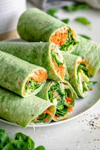 a platter with several veggie wraps piled on top of one another