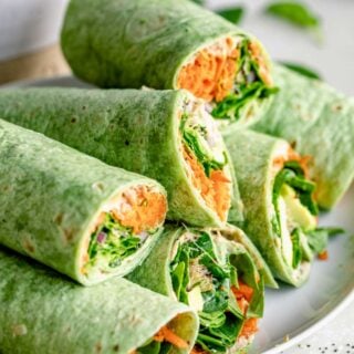 a platter with several veggie wraps piled on top of one another