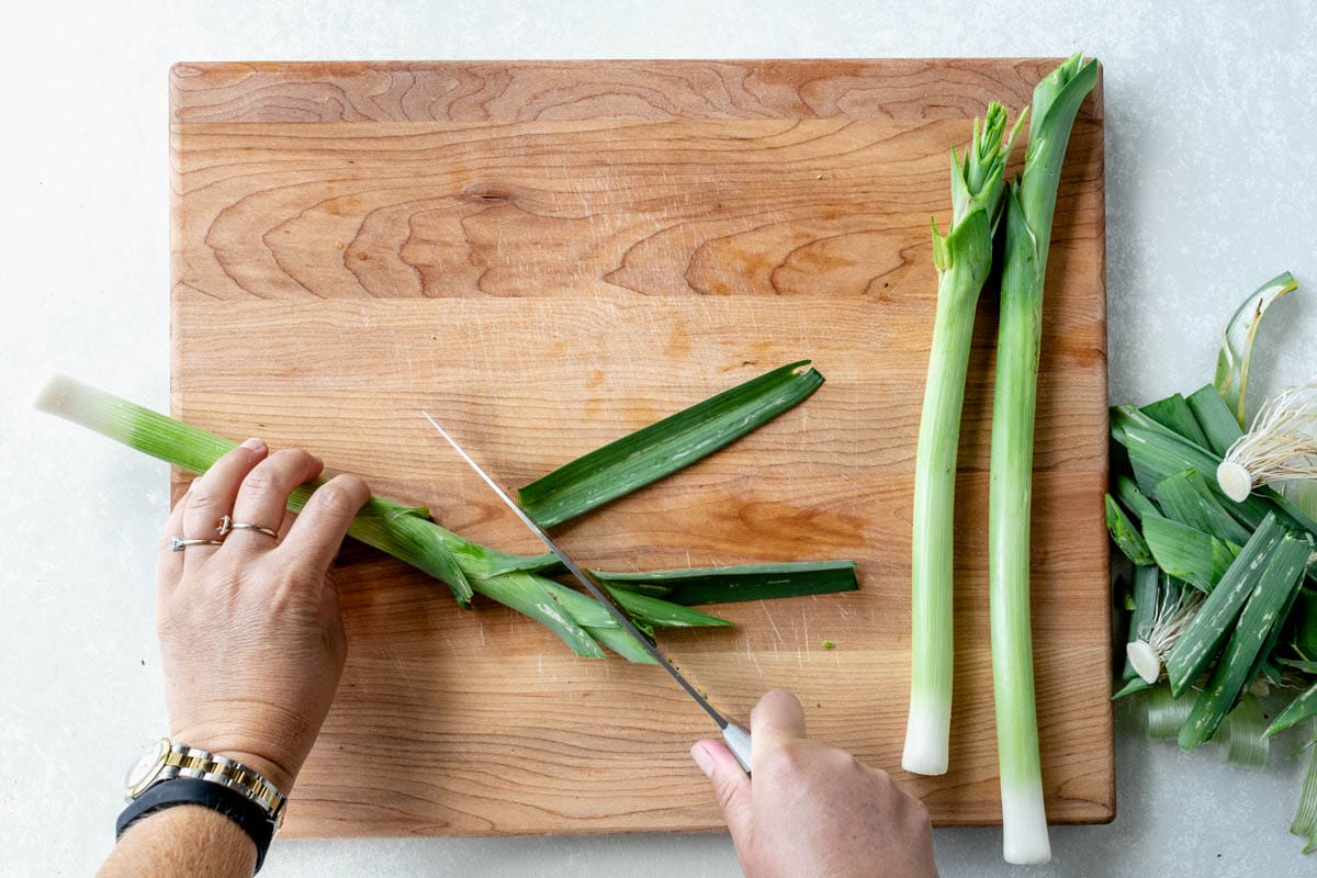 cutting the pithy greens off the top of the leeks