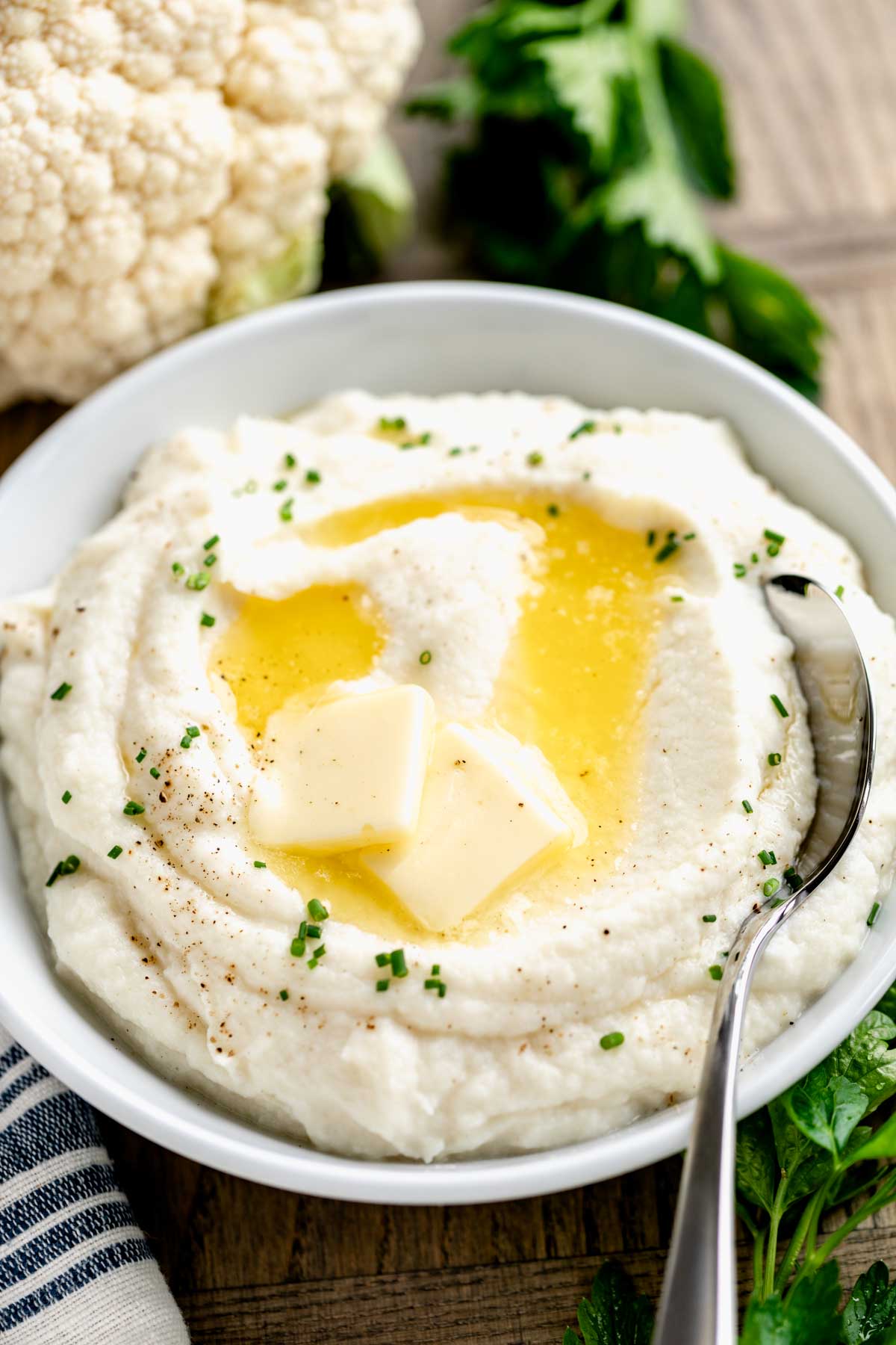 mashed cauliflower in a white dish with chives on top