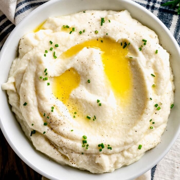 closeup of the bowl of mashed cauliflower with butter drizzled on top