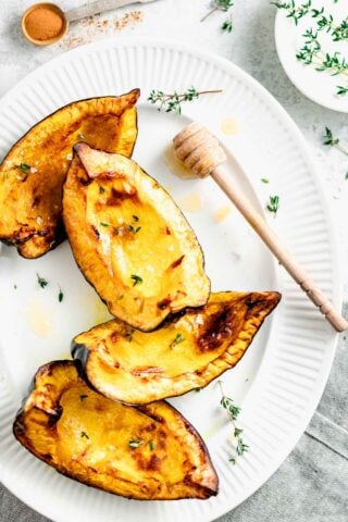 squash wedges on a white plate with a honey wand