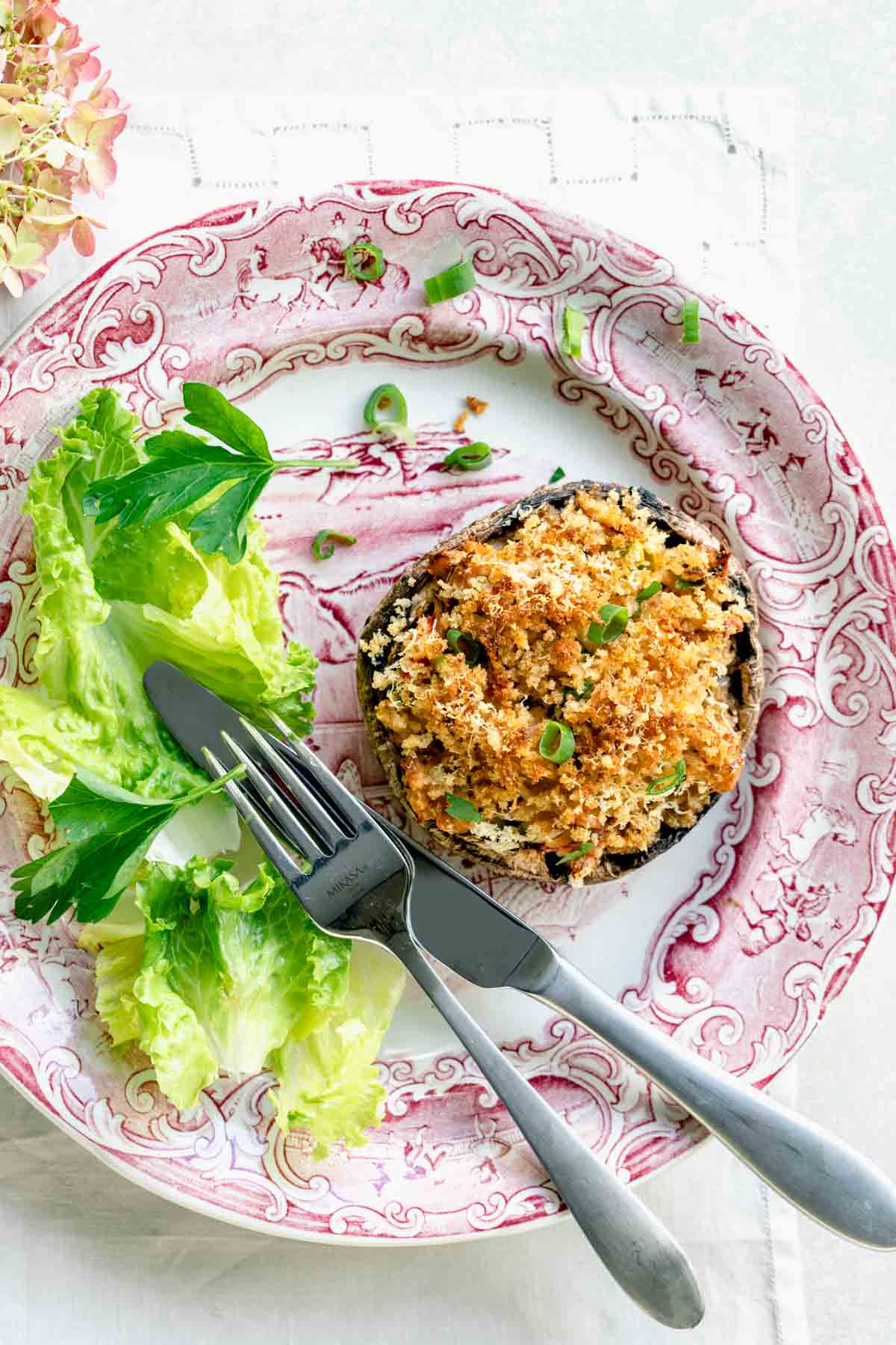 crab stuffed mushroom on a plate with lettuce and a fork and knife