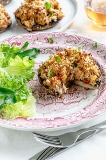 crab stuffed mushroom on a red and white plate with salad