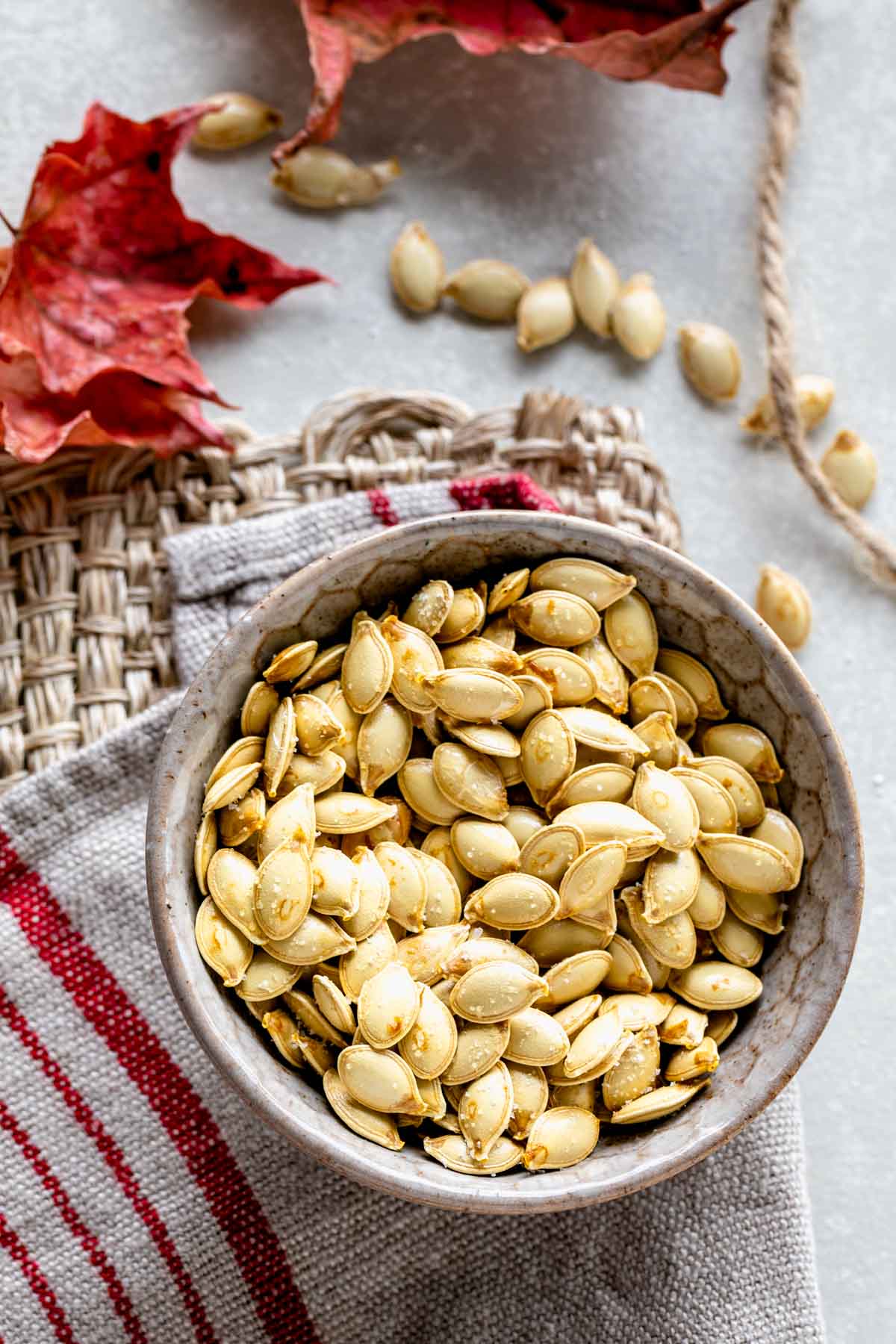 a bowl of roasted pumpkin seeds and dried maple leaves