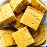 close up of squares of cornbread in a white dish with parchment