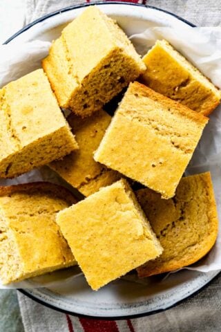 close up of squares of cornbread in a white dish with parchment