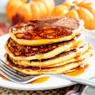 pumpkin pancakes with a fork on a white plate