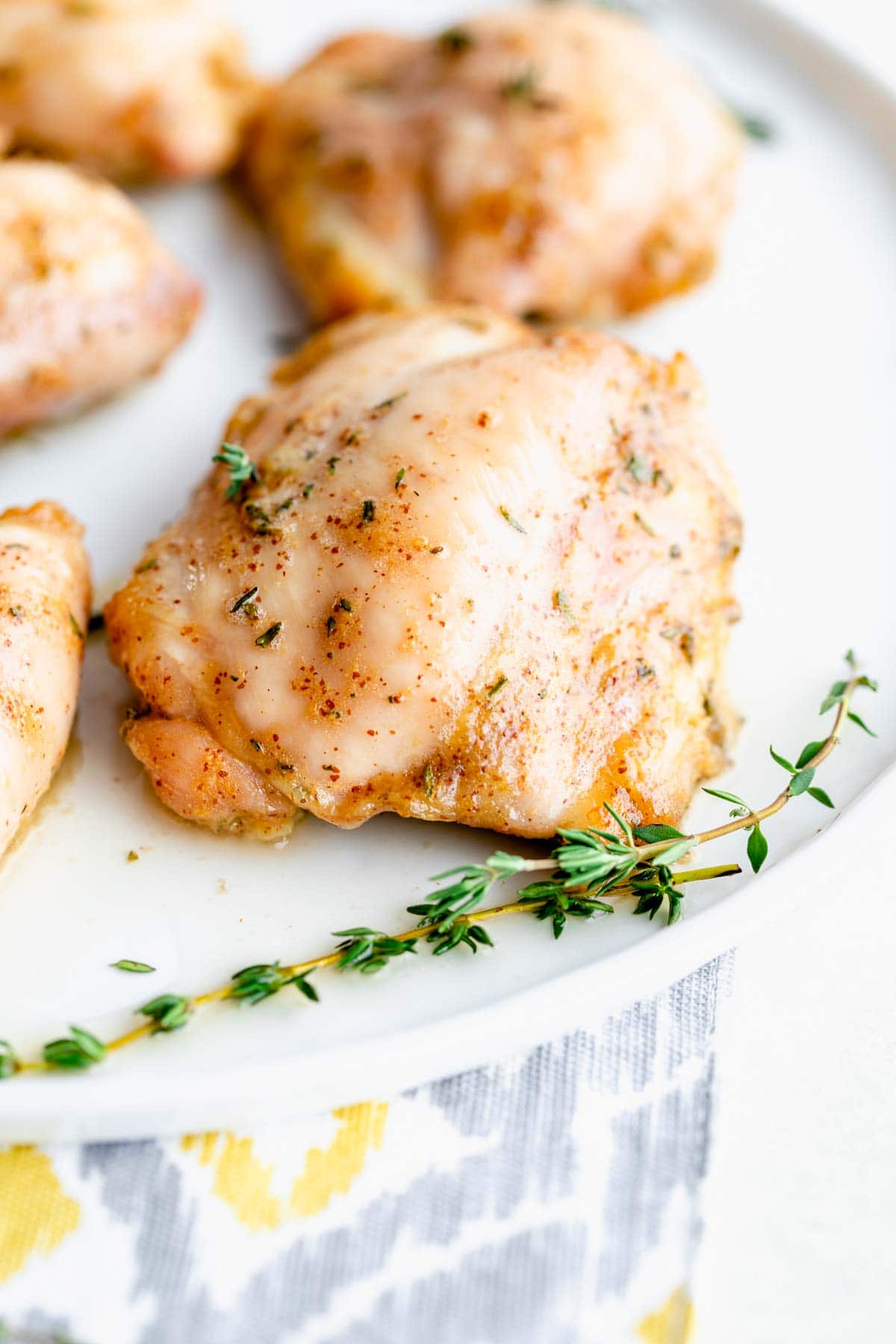 close-up of chicken thigh on a platter with fresh thyme sprigs