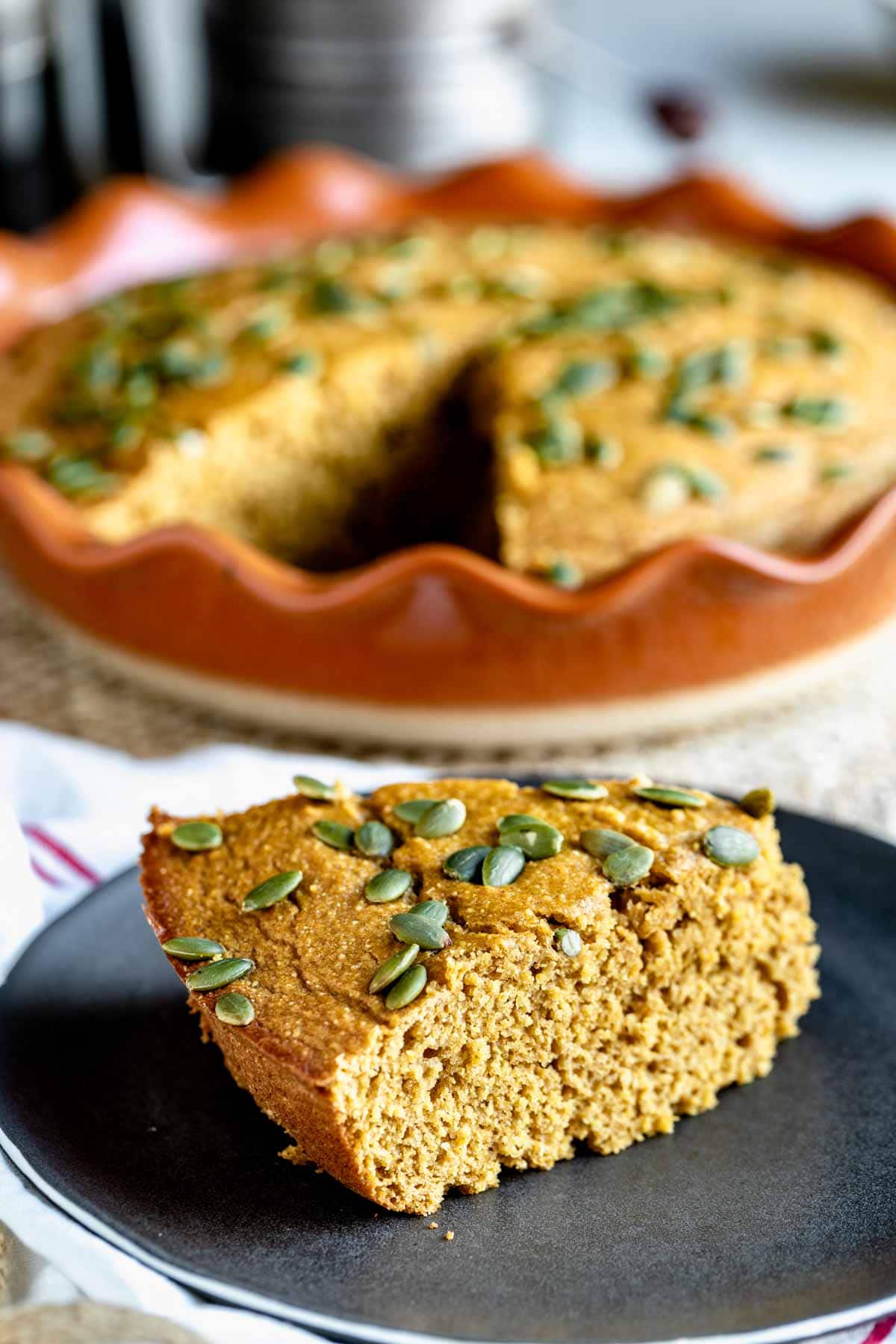 a wedge of pumpkin cornbread on a black plate