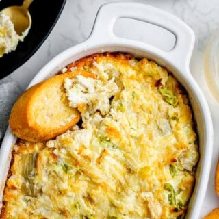 the dip in a crock with a baguette crostini in it