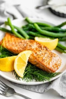 the salmon on a white plate with lemons and green beans