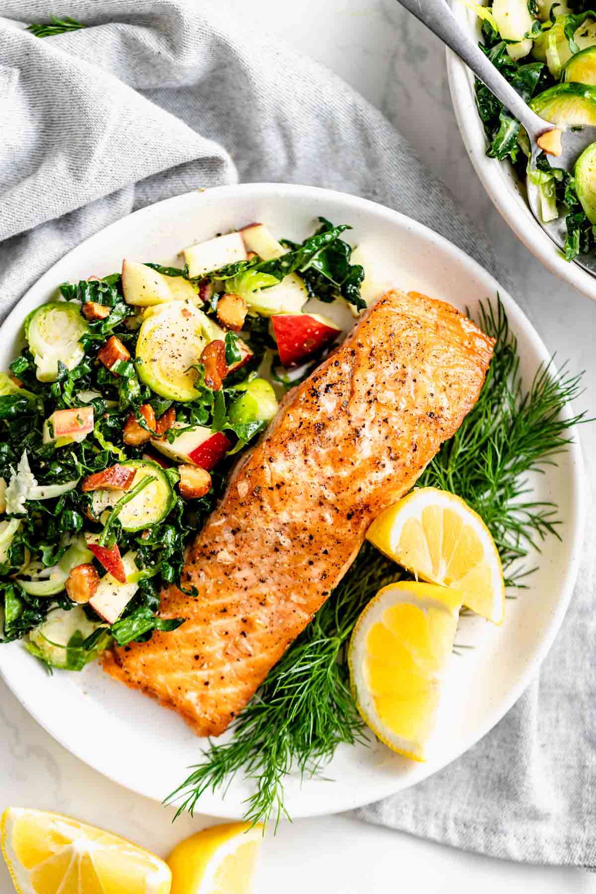 the salmon with shaved brussels sprout salad with kale on a white plate