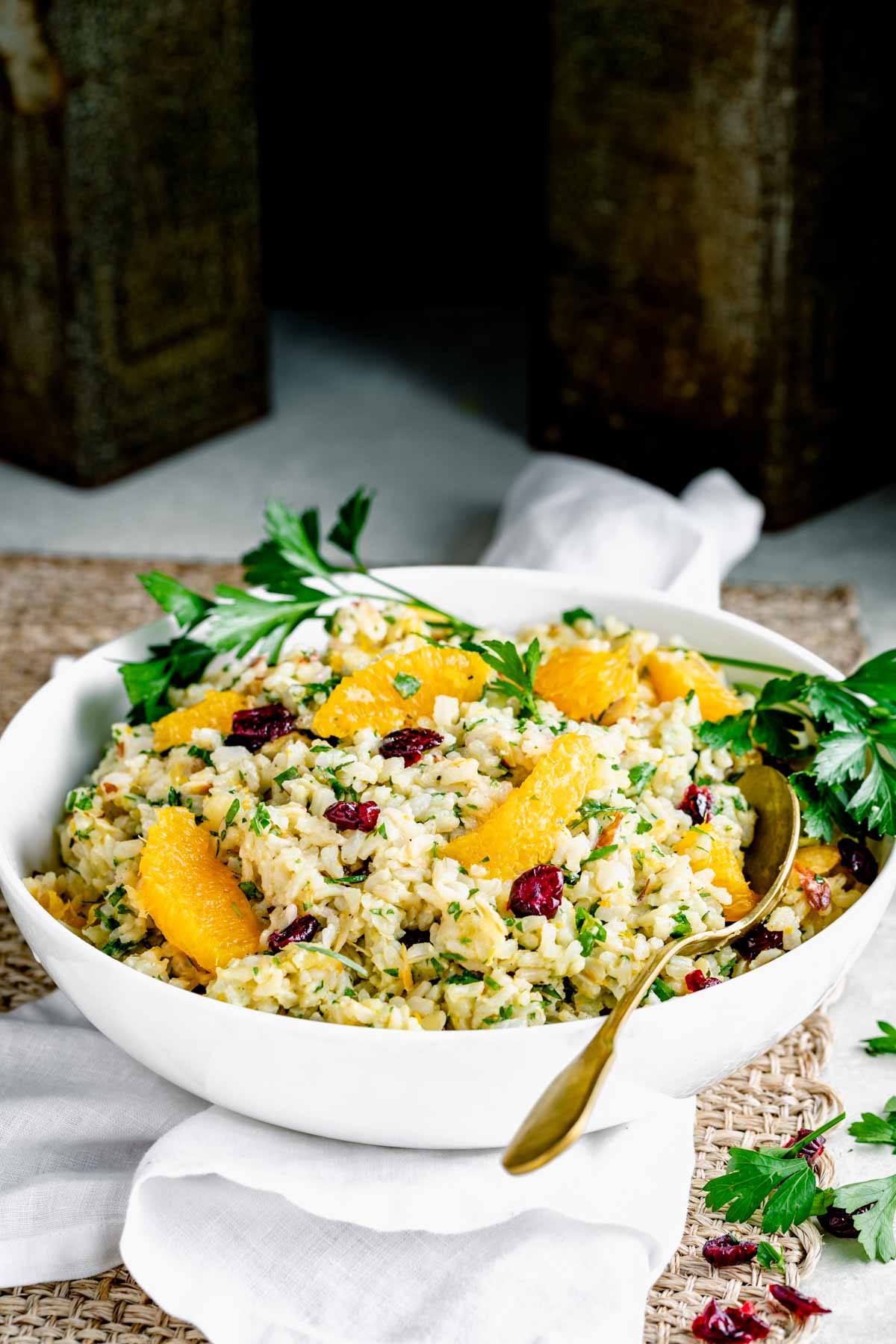 a bowl of brown rice salad with segments of oranges on top
