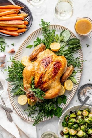 white table with platter of roast chicken and side dishes