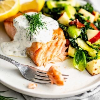 the sauce on a piece of salmon with salad on a white plate