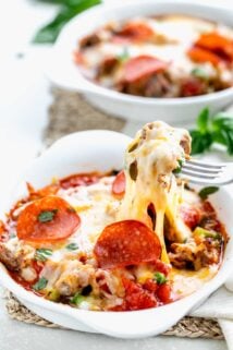 a cheesy scoop of the pizza bowl being lifted out with a fork