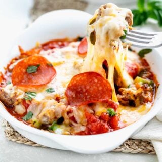 a cheesy scoop of the pizza bowl being lifted out with a fork