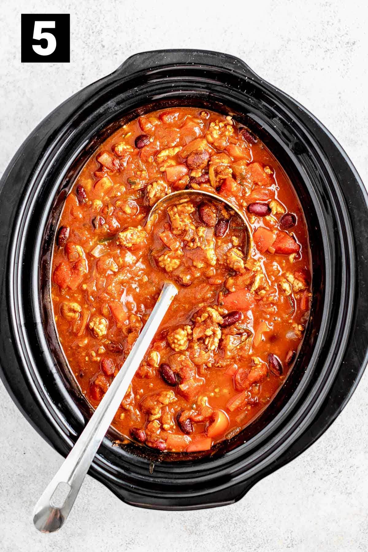 crockpot full of chili ready to serve with optional garnish