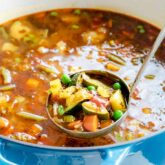 a blue pot with soup in it, and a ladle lifting a scoopful out