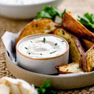 Greek Yogurt Sauce in a small bowl with a plate of steak fries