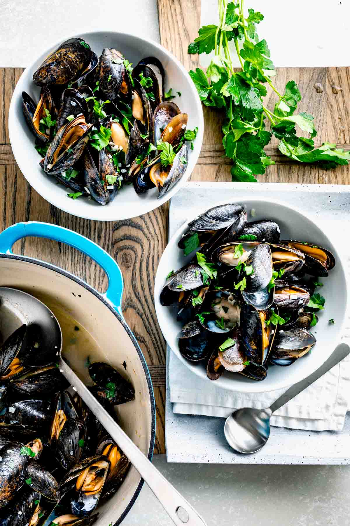 two bowls of mussels and a pot of mussels next to them