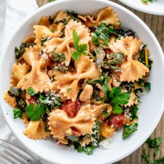 bow tie pasta in a bowl with swiss chard, beans, and creamy sauce