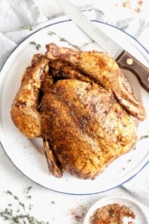 Overhead view of the whole chicken on a white platter with carving knife