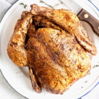Overhead view of the whole chicken on a white platter with carving knife