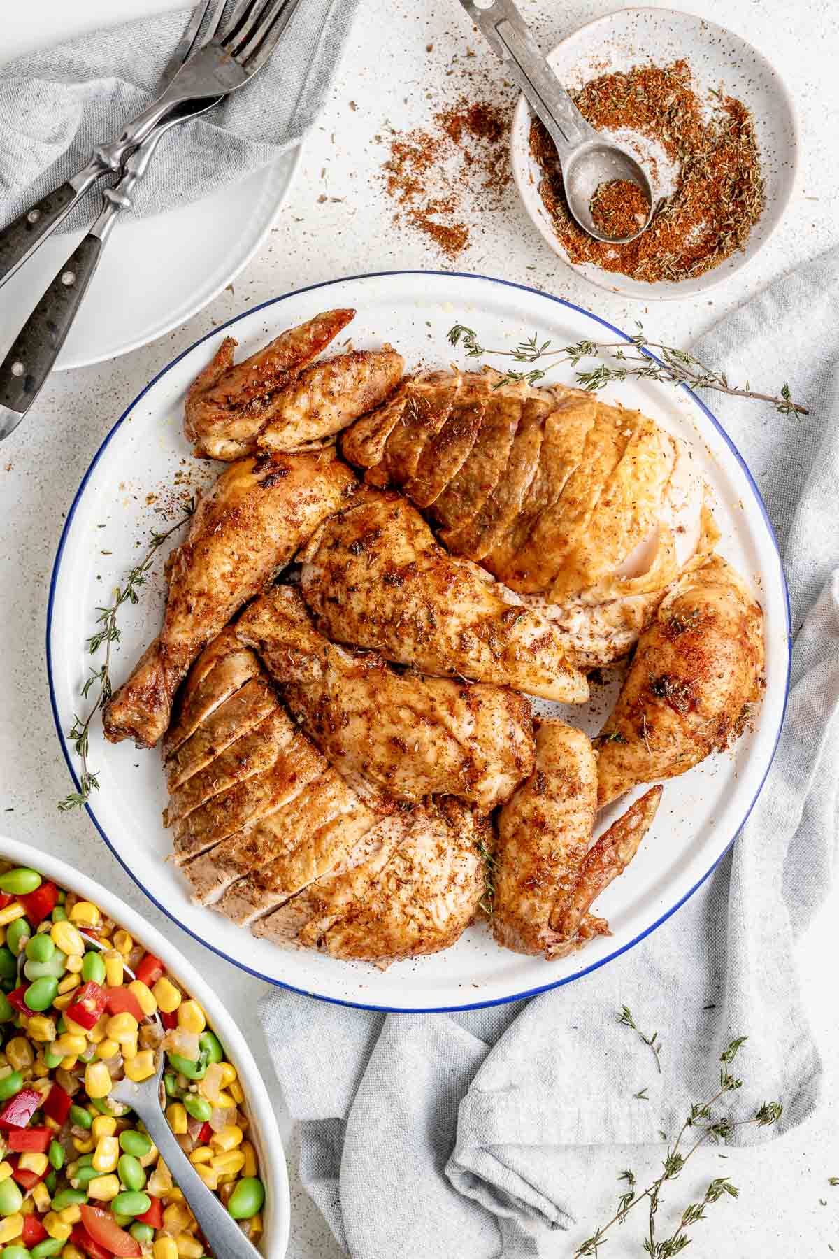 the roast chicken carved and arranged on a platter with succotash on the table too