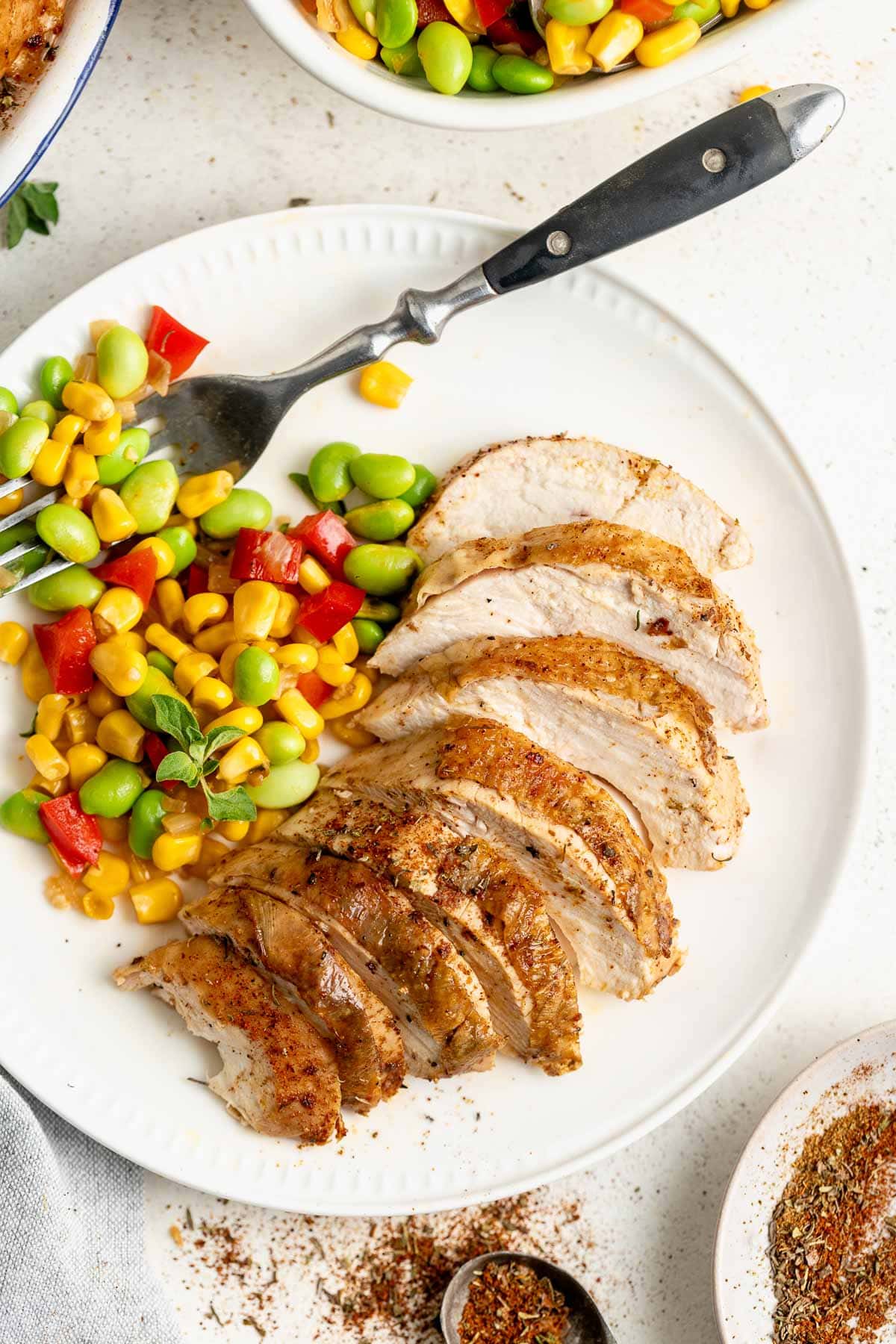 the plated chicken with succotash with a fork