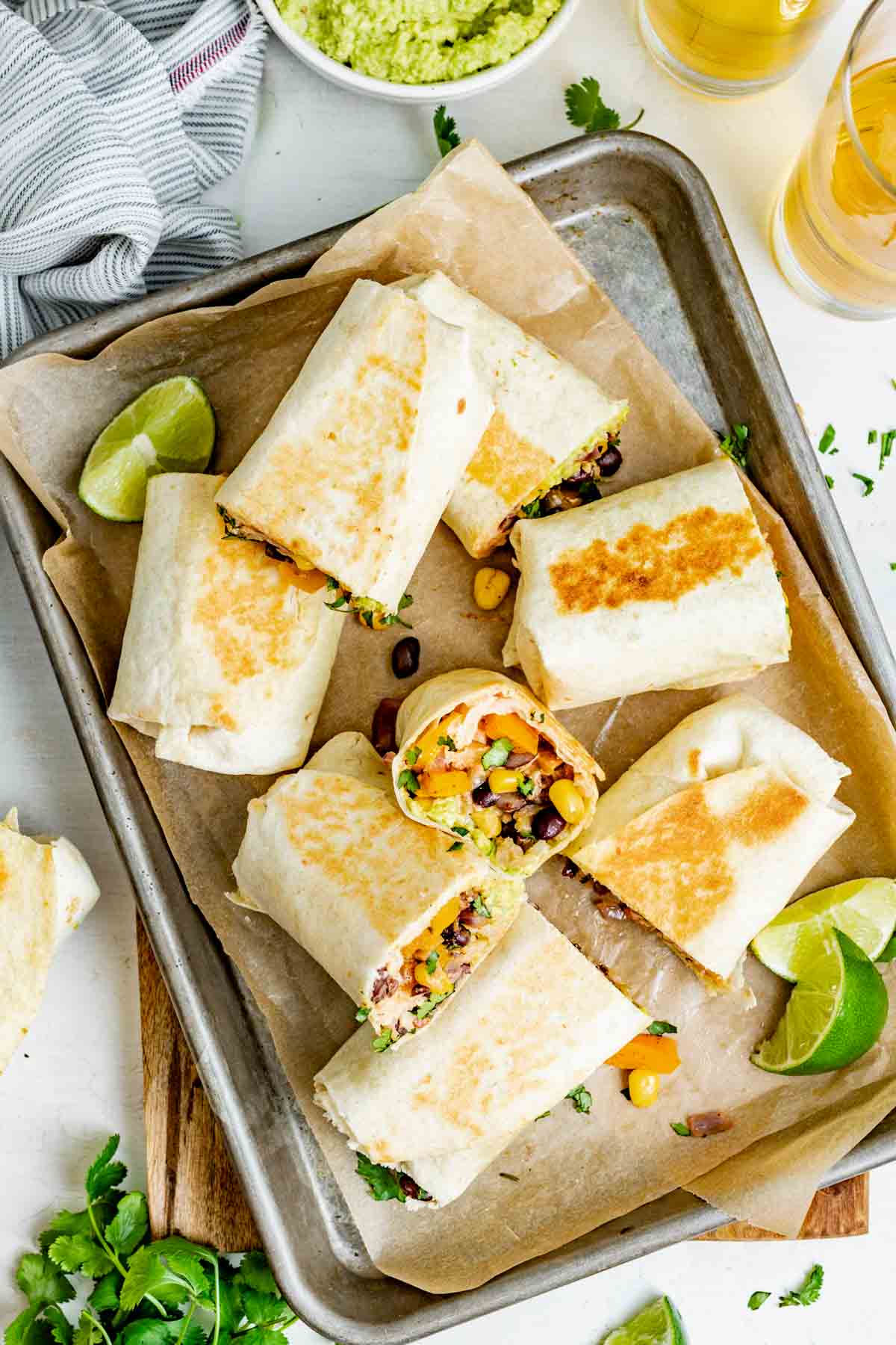 8 halves of vegetable burritos on a parchment lined cooking sheet either laying flat on the sheet or up against the side of another