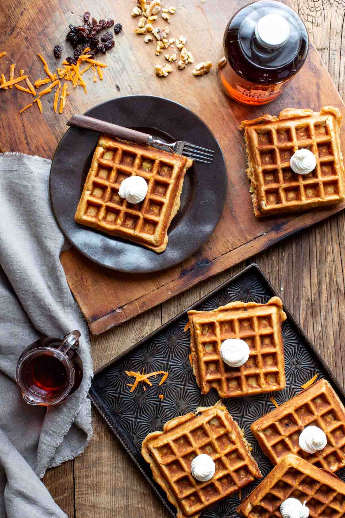 several waffles on a cutting board, baking sheet and plate from overhead on a wooden table