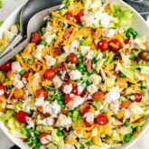 the chopped chicken salad in a white bowl with serving utenstils