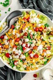the chopped chicken salad in a white bowl with serving utenstils